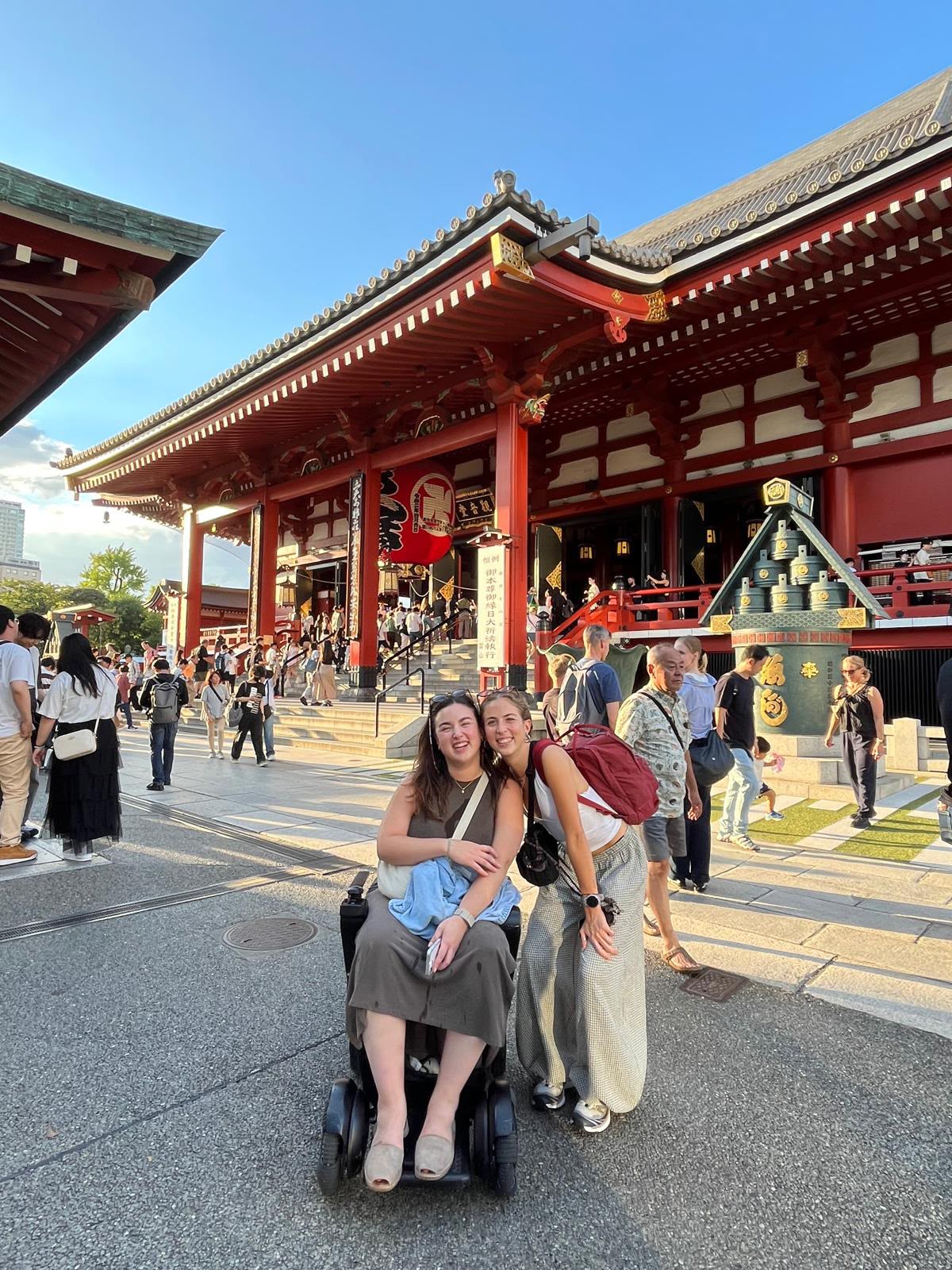 浅草寺の本堂前で、笑顔を見せる車いすを利用するお客様と同行者。